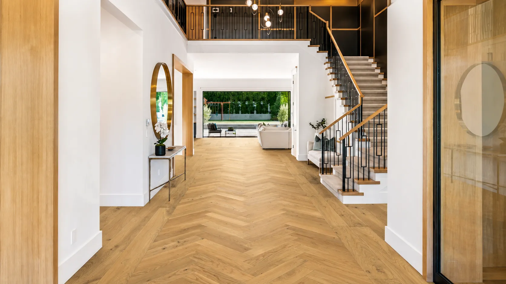 herringbone hardwood flooring with a straight-plank border in a bright entryway with staircase